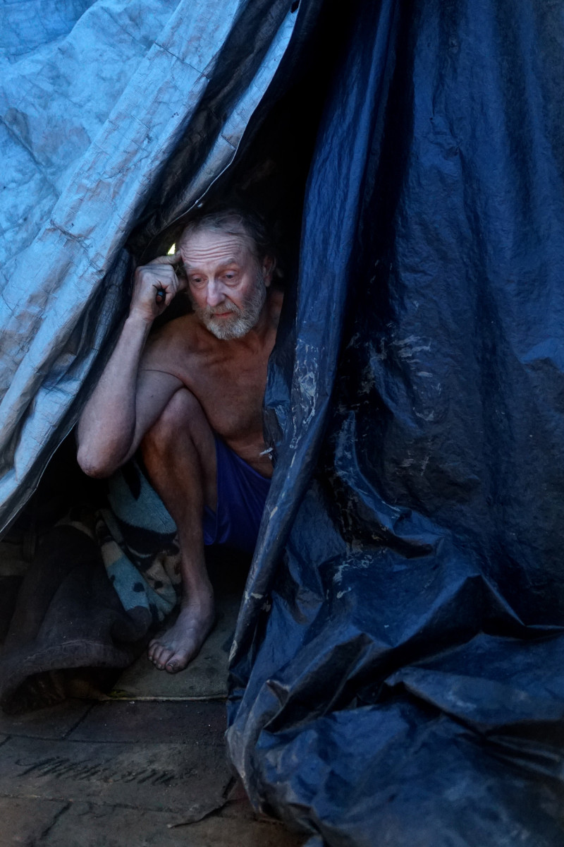 Doug Wynne pokes his head out of his tent where he's been living for the past four years. Wynne came to San Jose from Florida hoping for a job in the tech industry, but feels he was too old to be viewed as a desirable employee. (James Tensuan/KQED)