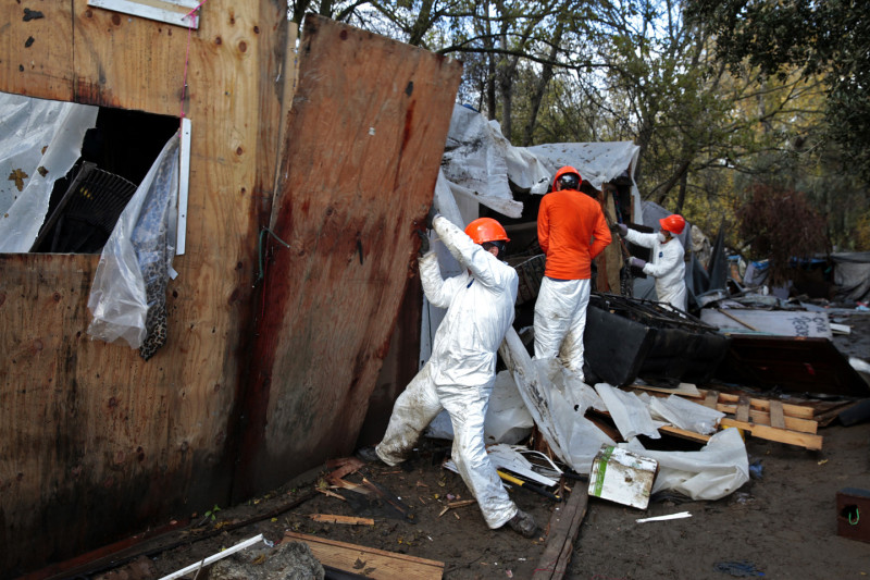 A work tears down a wall at The Jungle. (James Tensuan/KQED)