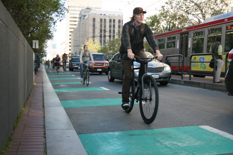 Cyclists ride on green bike lanes on Market St.