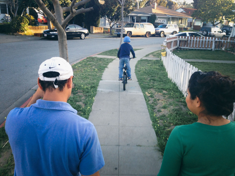 Stephanie and Jose watch their son ride a bike at their new home.