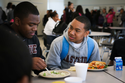 Diamond Allen (right) eats lunch in the cafeteria of his new school, Eastside College Preparatory School in East Palo Alto. (Jeremy Raff/KQED)