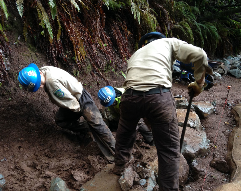 California Conservation Corps members, “Cs” for short, roll rocks as heavy as 500 pounds to their work area, set them into place and chisel them for a snug fit.
