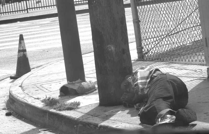 An unidentified passed out on the sidewalk of a Skid Row back street.