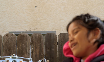 Jacquelyn Funes, 9, on her front porch. A bullet hole can be seen in the wall behind her. 