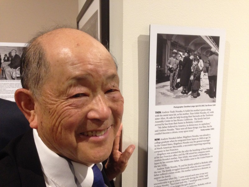 Andrew Nozaka visits the California Museum in Sacramento. He's next to a photo of him and his mother taken by Dorothea Lange at Tanforan in 1942.