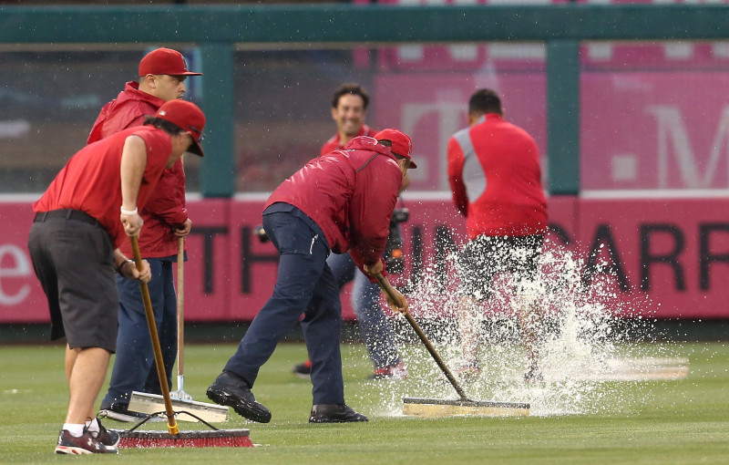 Members of the grounds crew at Angels Stadium in Anaheim tries to clear the outfield of excess water before Sunday's game with the Boston Red Sox. The game was eventually postpone -- the Angels' first rainout since 1995. 