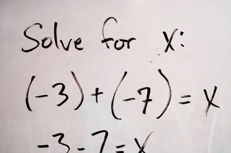 An algebraic equation is displayed on whiteboard.