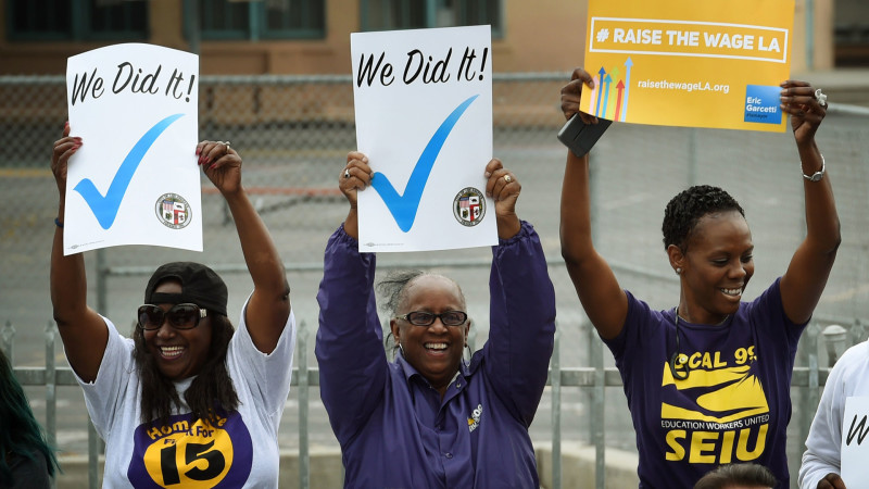 Labor activists celebrate as Los Angeles Mayor Eric Garcetti signs into law an ordinance raising the minimum wage to $15 by 2020 on June 13, 2015.