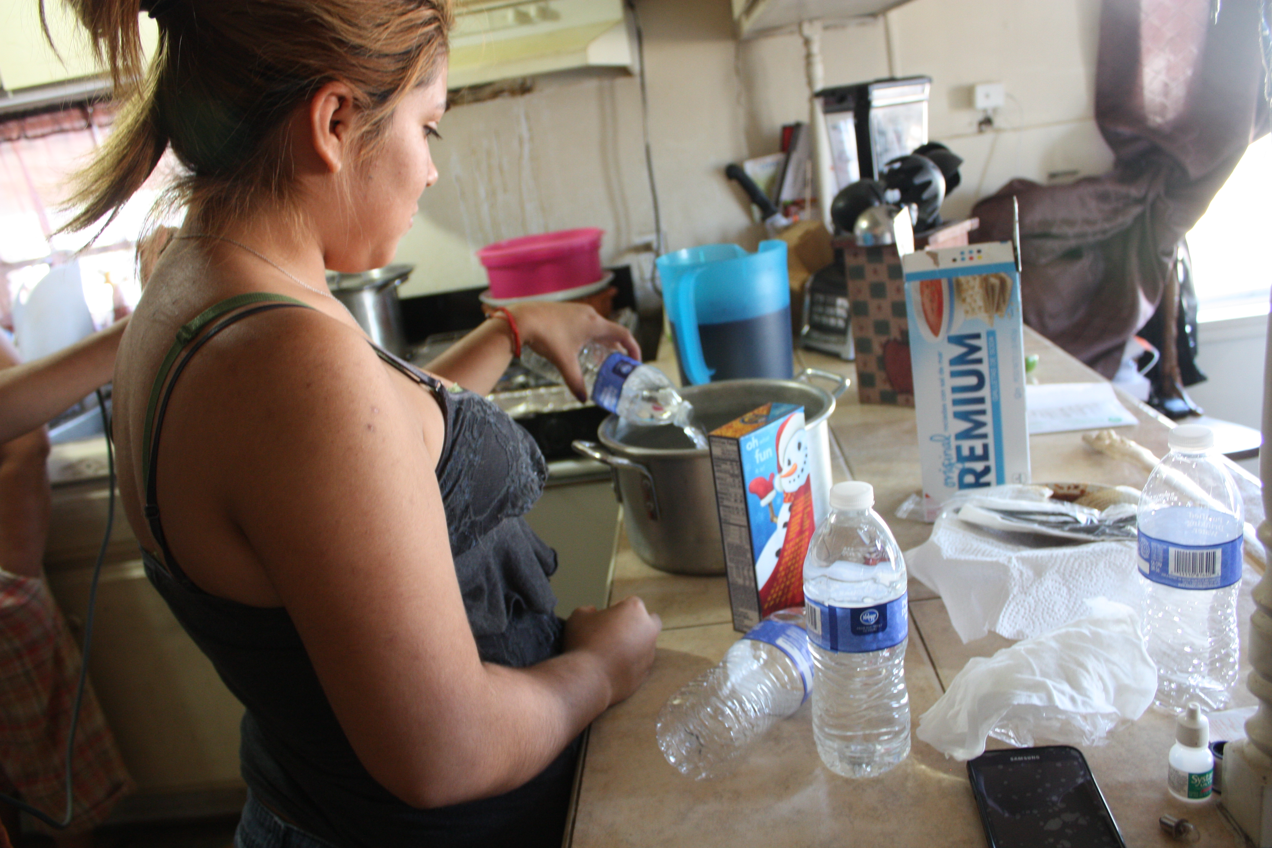 Medina’s daughter Guadalupe prepares for dinner, pouring bottles of water into a pot to make macaroni and cheese. 