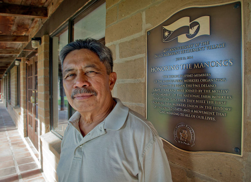At the Agbayani Village, a retirement home built for the Manongs, Roger Gadiano stands next to a plaque honoring the Manong Filipino workers who started the 1965 grape strike.