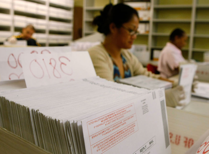San Francisco Department of Elections workers sort stacks of vote-by-mail ballots.