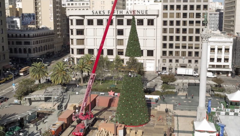 Workers use a crane to lift the final segment of the tree into place. 
