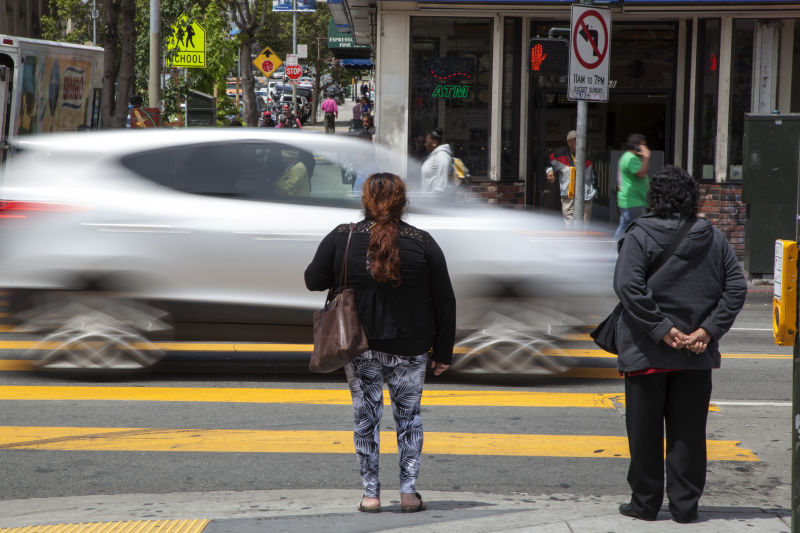Pedestrians wait to cross 24th Street in the Mission. 