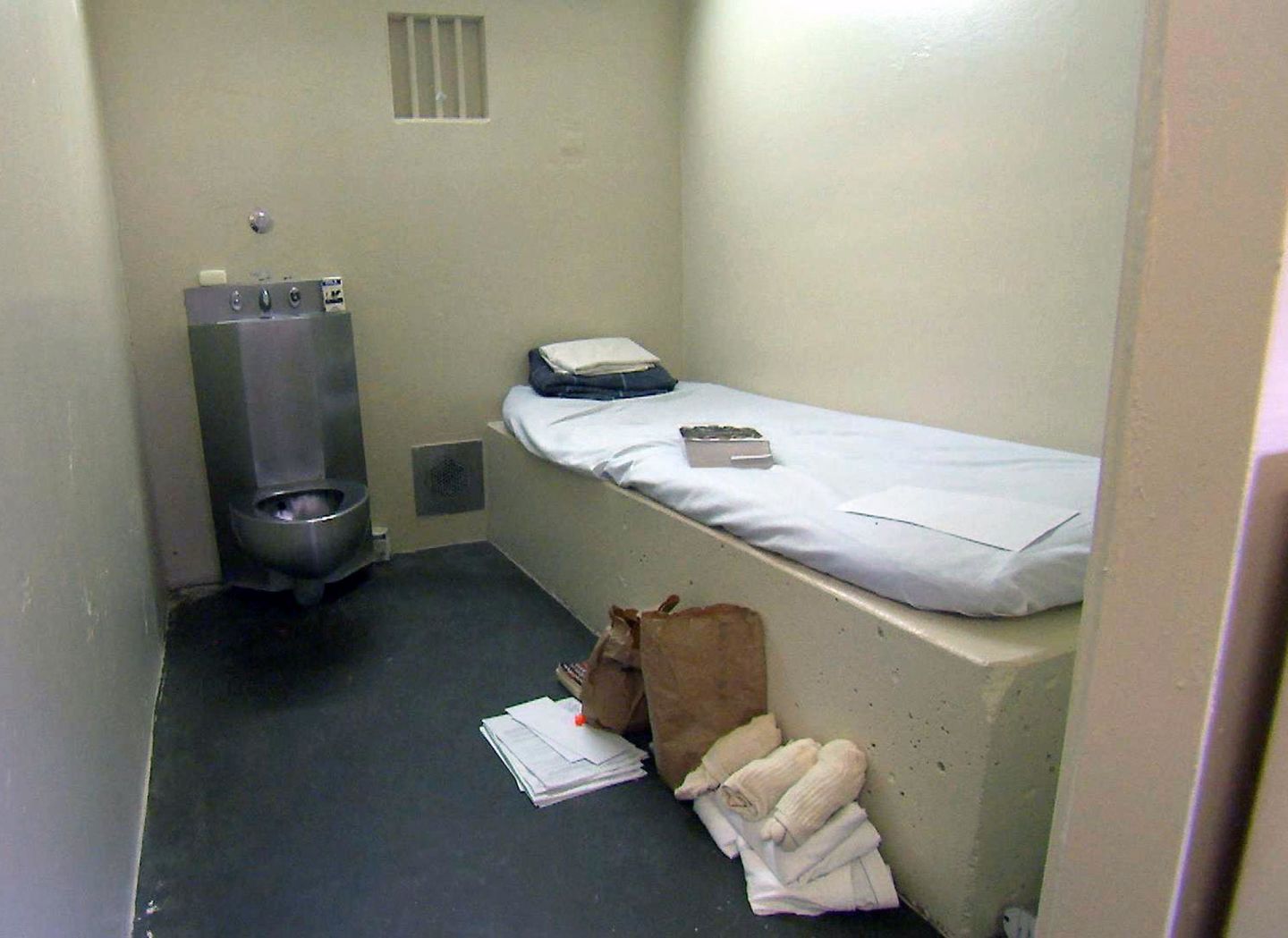 A concrete block and a thin mattress make up the bed for some cells on death row. The toilet is metal, there is no rug, just a concrete floor.