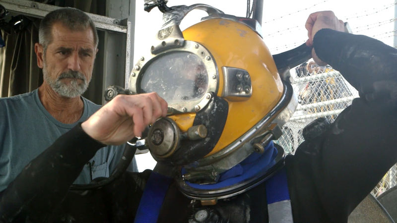 Diver Kevin Nekimken puts on his helmet before a recent dive at the Port of Oakland. (Alan Toth/KQED)