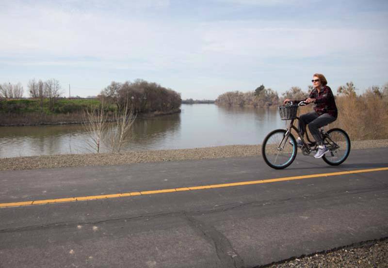 A bicyclist rides along a public levee in the Pocket, Thursday, February 11, 2016. Will Cannady, who lives in the neighborhood, is pushing for the city to buy privately owned land along the Sacramento River to complete a new bike trail. 