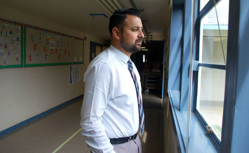 Oak Ridge Elementary School Principal Daniel Rolleri looks out a hallway window as he makes the rounds on campus. The school serves low-income families in a challenging neighborhood in Sacramento.
