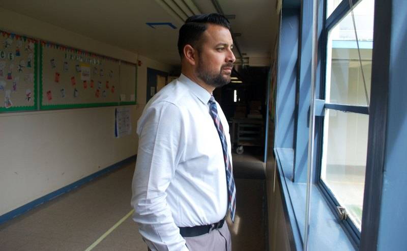 Director de Oak Ridge Elementary Daniel Rolleri ve por una ventana del pasillo en lo que recorre la escuela. La escuela sirve a familias de reducidos recursos en un vecindario difícil de Sacramento. 