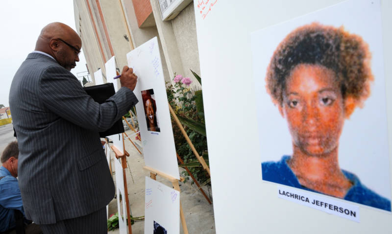 Rev. Dr. Kelvin Calloway leaves a message on photographs set up as a memorial for 10 of the victims of the Grim Sleeper serial killer, in Los Angeles in 2010.