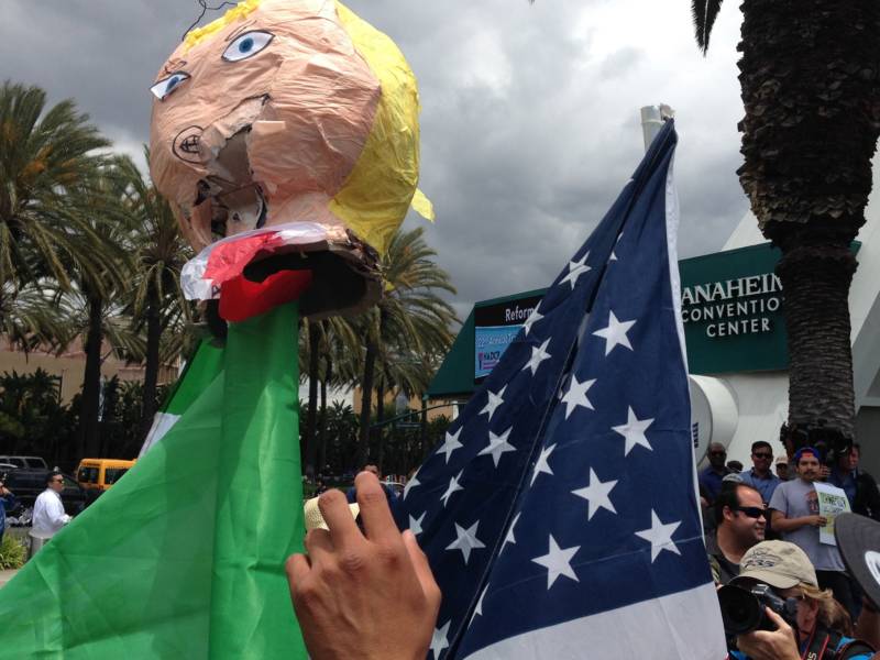 The head of a Donald Trump piñata is impaled on an American flag and paraded outside the Anaheim Convention Center on Wednesday.