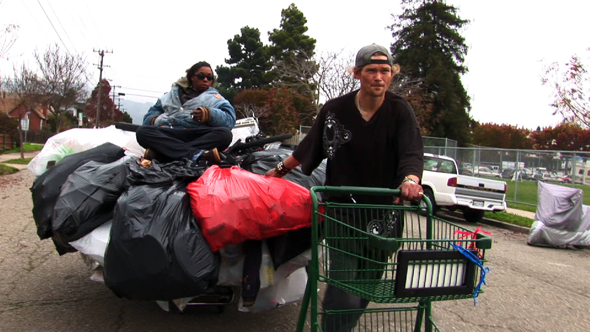 Jason Witt (right), the Olympic champion of recycling, hauls a shopping cart with his girlfriend, Heather Holloman (left), on top. 