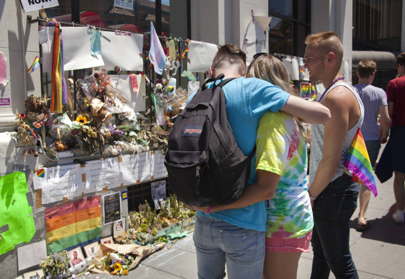 Three friends console each other in front of a memorial for the victims of the Pulse Nightclub shooting in Orlando, Florida on the corner of 18th and Castro Streets.