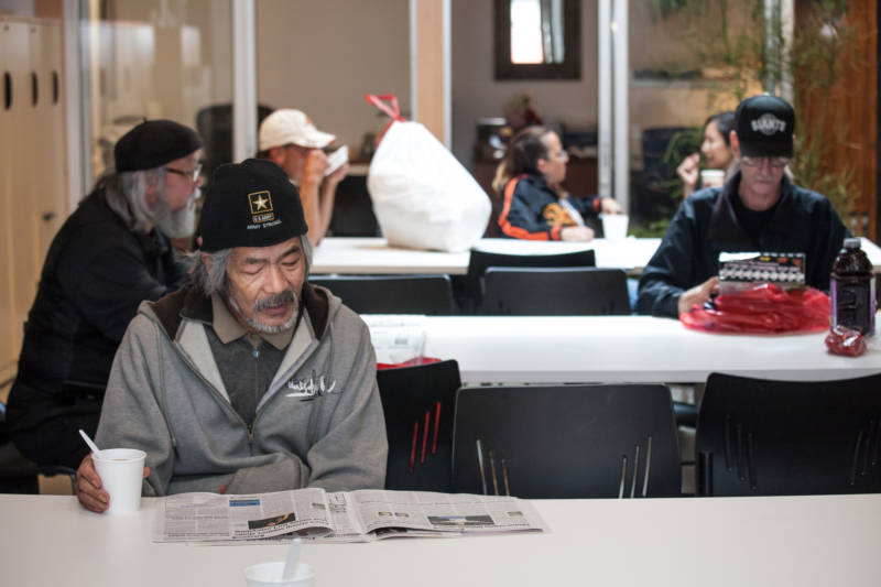 Hideaki Hirama reads the paper and eats his breakfast at the North Beach Citizens center.