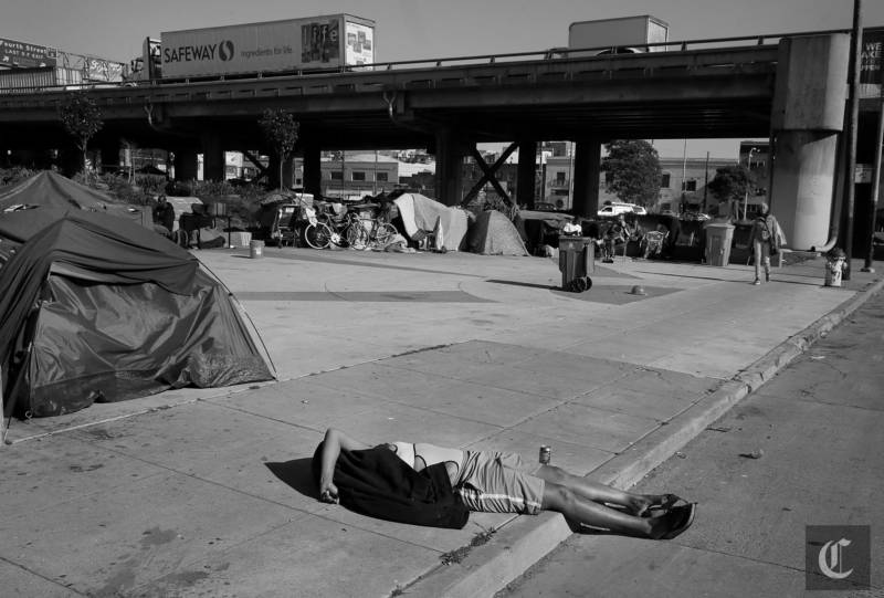 A homeless woman from the encampment on 5th Street near the Bay Bridge entrance laid in the sidewalk and street Tuesday March 3, 2015. Homeless encampments are still prevalent in San Francisco, Calif. and their locations are becoming more apparent.