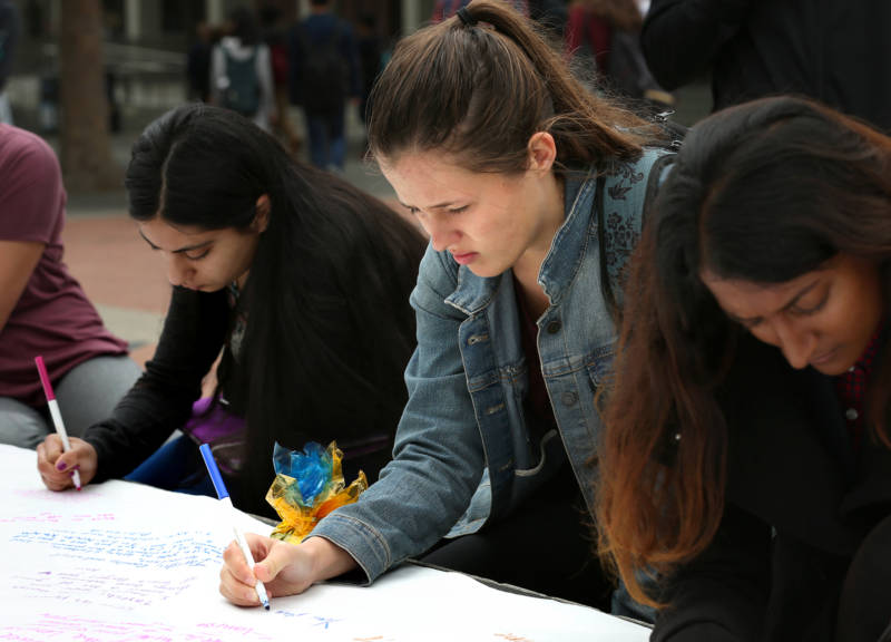Tarishi Jain's roommate, Hannah Rowe, writes a message to Jain on a banner during a vigil for the 19-year-old UC Berkeley student, one of the victims of an attack at a Dhaka cafe in Bangladesh on July 2,2016. The vigil was held on UC Berkeley's campus in Berkeley, Calif. on July 5, 2016.