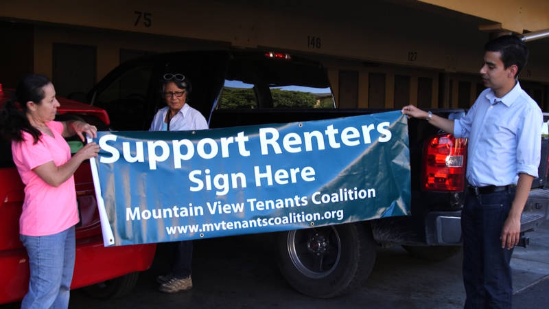 Lourdes Rangel (left) and Evan Ortiz hold a banner for the Mountain View Tenants Coalition.