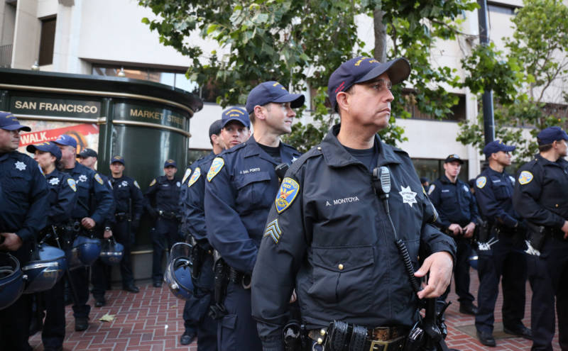 A San Francisco Police Officer looks on as protestors chant: "These racist cops have got to go." 