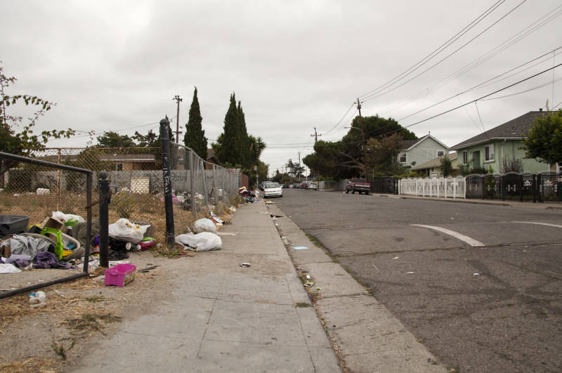 Abandoned trash sits along the sidewalk and in an empty lot on 105th Avenue in the Madison Park neighborhood in Oakland on Aug. 26, 2016.