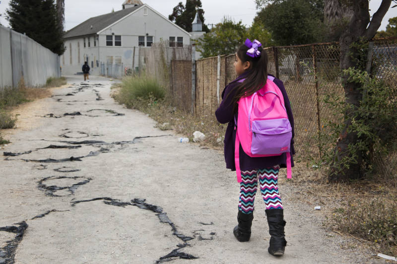 Seven-year-old Celia Fragoso walks through her neighborhood in Madison Park in the morning on her way to Sobrante Park Elementary in Oakland on Aug. 26, 2016.