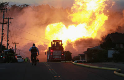 A law enforcement official runs towards a massive fire in a residential neighborhood September 9, 2010 in San Bruno, California.