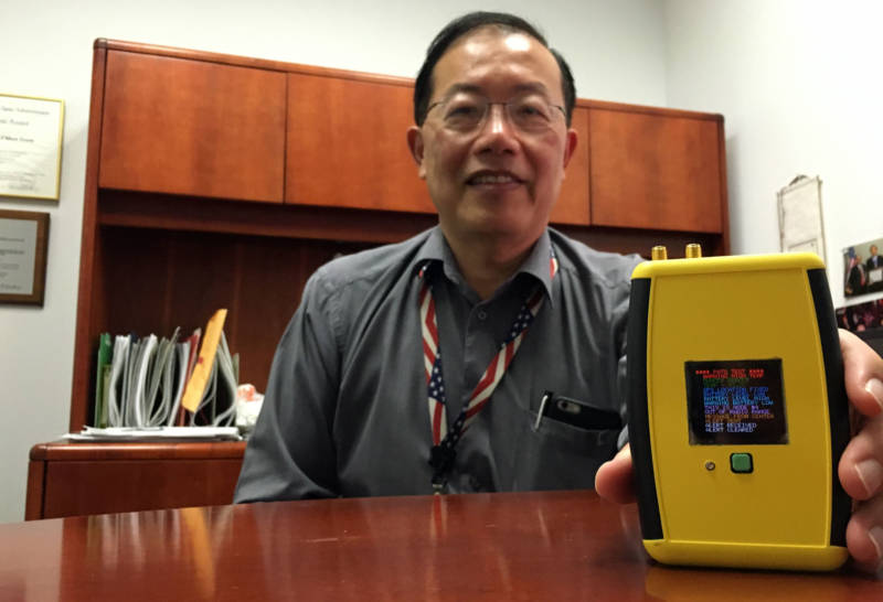 Ed Chow with NASA's Jet Propulsion Laboratory shows off the Personal Alert and Tracking System he helped develop for firefighters.