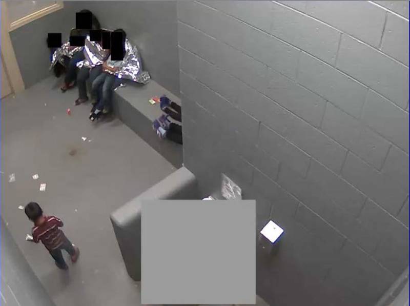 At the Border Patrol's Naco detention facility, adults and children sit in a cell with Mylar sheets and no mats