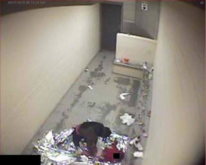 In September 2015, a woman changes a child's diaper on a Mylar sheet in a dirty concrete cell.