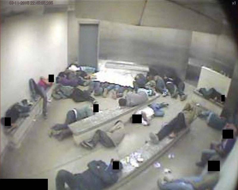 Men at a Border Patrol facility in Douglas, Arizona, sleep on concrete floors and benches, with several men crowded under one Mylar sheet.