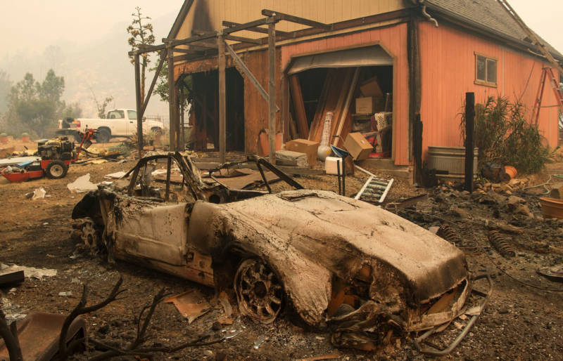 A burned out Porsche sits near a home partially burned by the Loma Fire in the Santa Cruz Mountains on September 27, 2016.