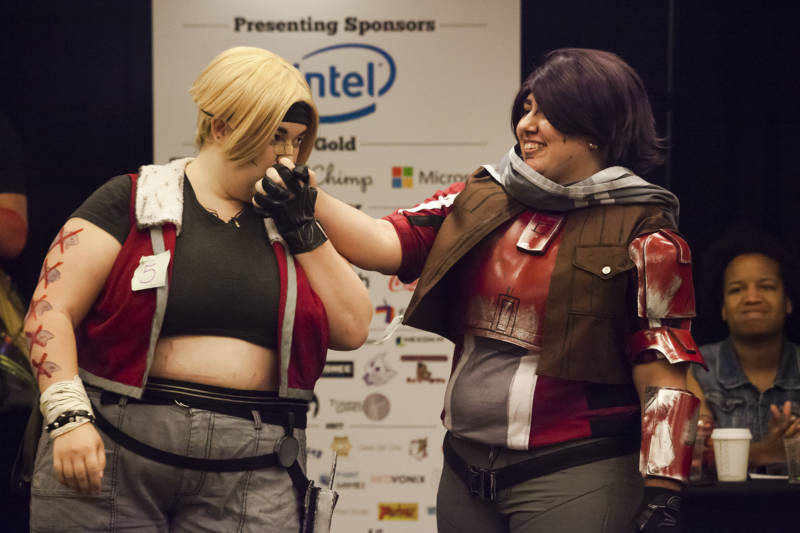 Two cosplayers costumed as Janey Spring (left) and Athena the Gladiator (right) from Borderlands the Presequel hold hands and kiss on stage during the GX4 Cosplay Pageant at the GaymerX Convention. 