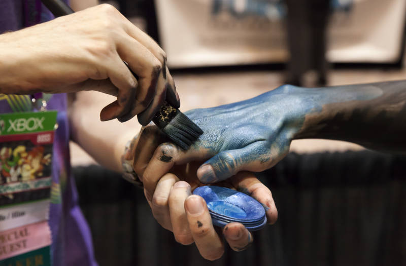 Brandon McGill begins painting the hand of model Ty Monzingo. 