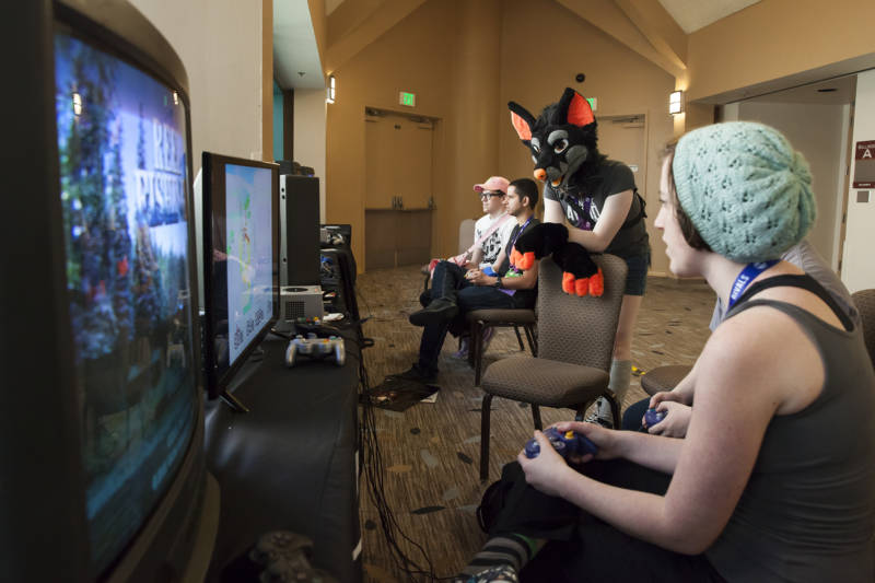 Sam (center) watches as two of her friends play video games in the Magfest Arcade. 