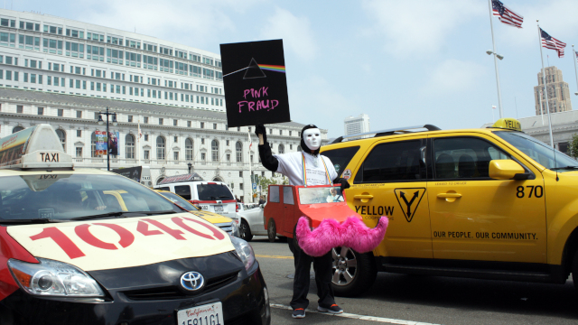A protester mocks ride service Lyft and its signature pink mustaches atcab driver rally outside San Francisco City Hall in 2013. (Alex Emslie/KQED)