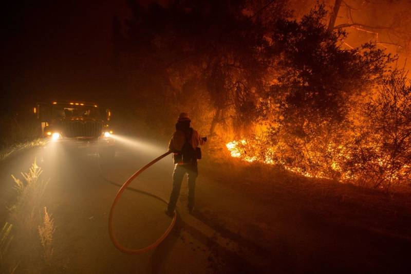 Sampson Spence of Fremont Fire douses flames as they approach a road in the Santa Cruz Mountains near Loma Prieta, California
