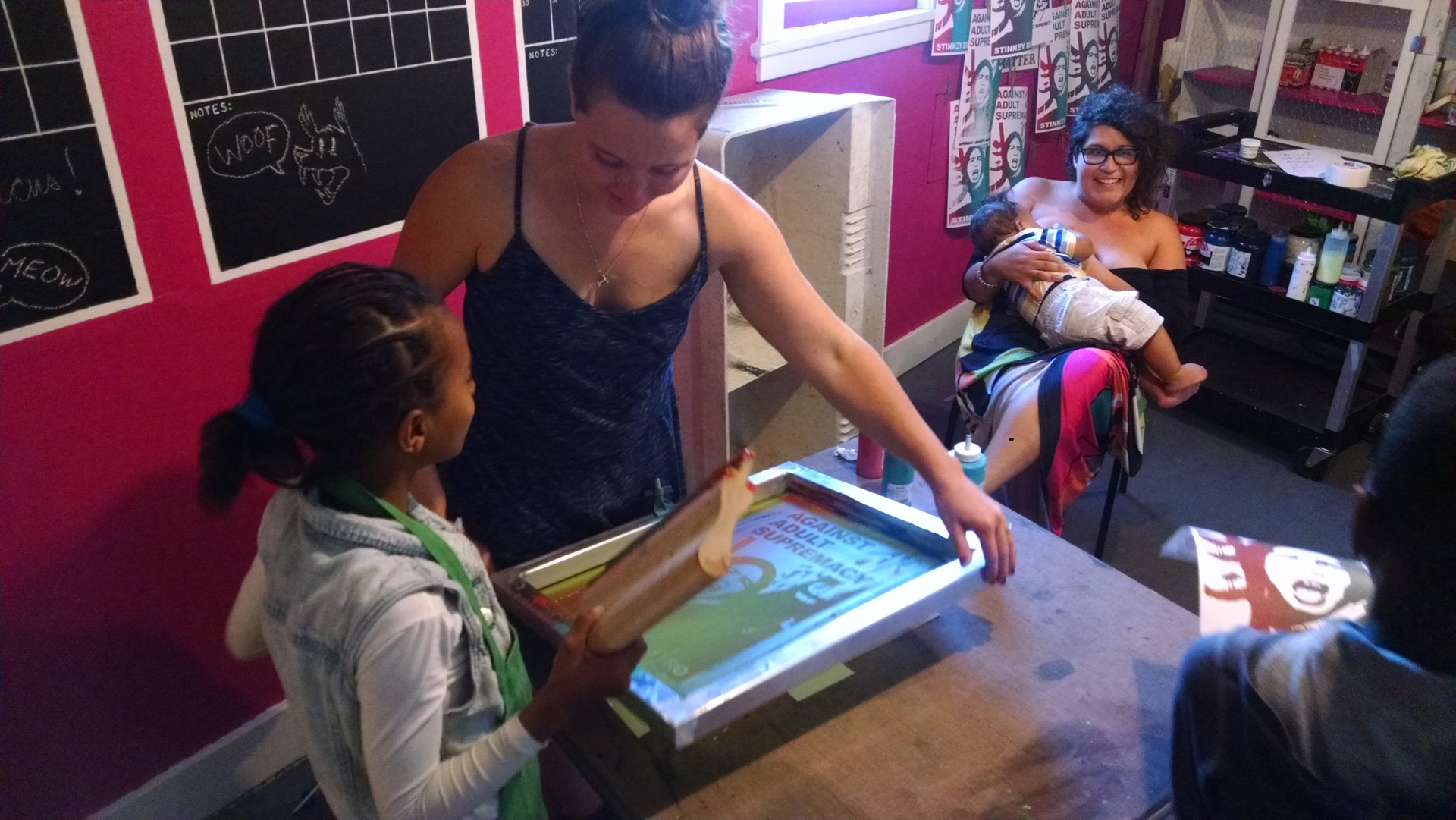 Franki Velez (with baby) helps teach screenprinting at the Omni Commons.
