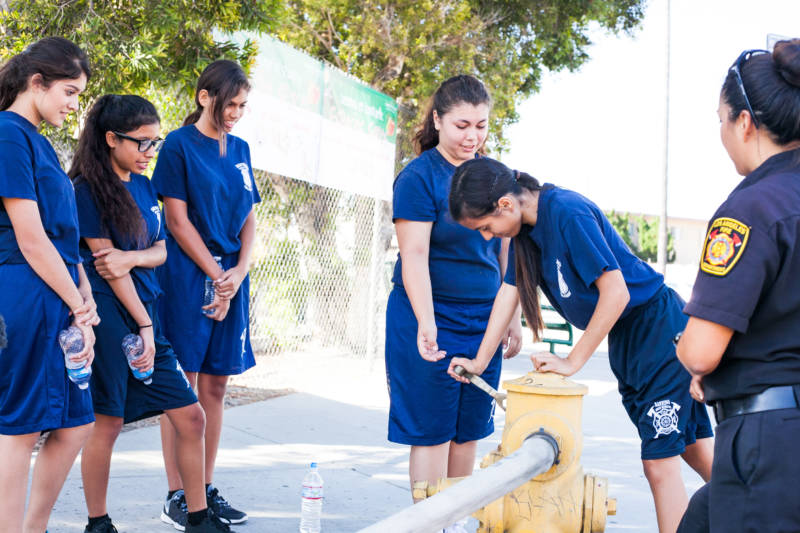 Gail Sonoda (R), an instructor and firefighter with the Los Angeles Fire Department, teaches young cadets how to work a hydrant.