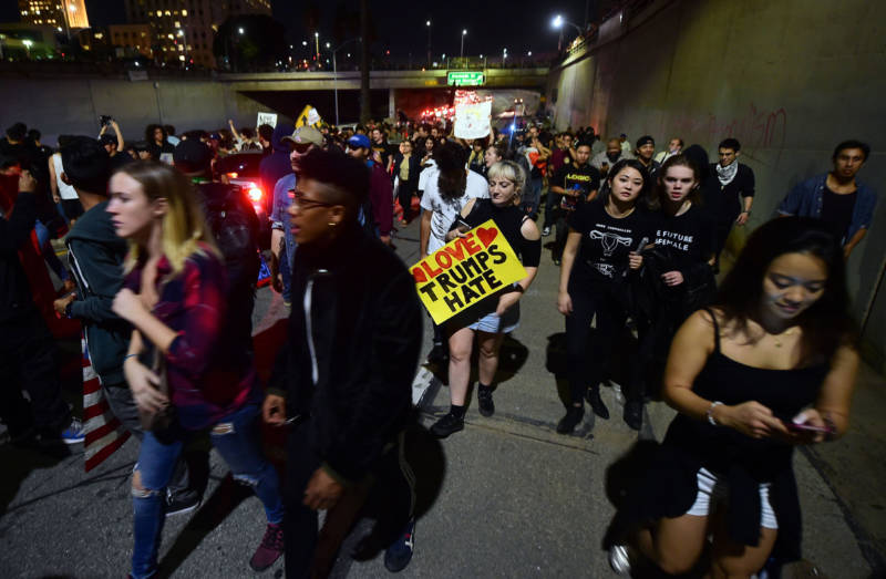 Protesters walk back up a freeway onramp amid a chaotic traffic situation with the shutdown of the freeway in downtown Los Angeles after midnight early on November 10, 2016.