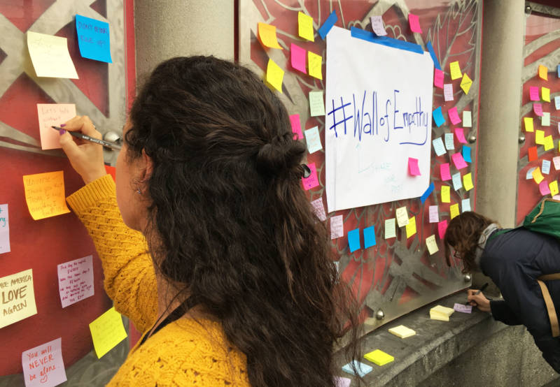 People attach messages of support and empathy to the walls at the 16th St. BART station in San Francisco. 