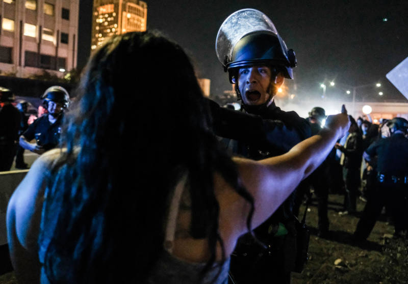 A protester (foreground) confronts a police officer as demonstrators shut down the 101 Freeway in Los Angeles Wednesday night.