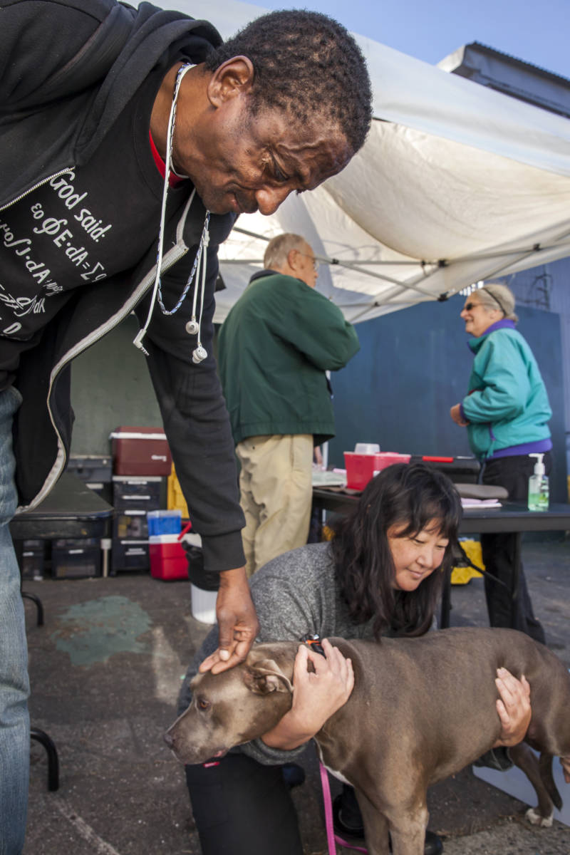 Lawrence Gomez (left) strokes the head of his seven-year-old pit-bull, Diamond, when her paws are checked during the monthly Vet S.O.S clinic in San Francisco, California. 